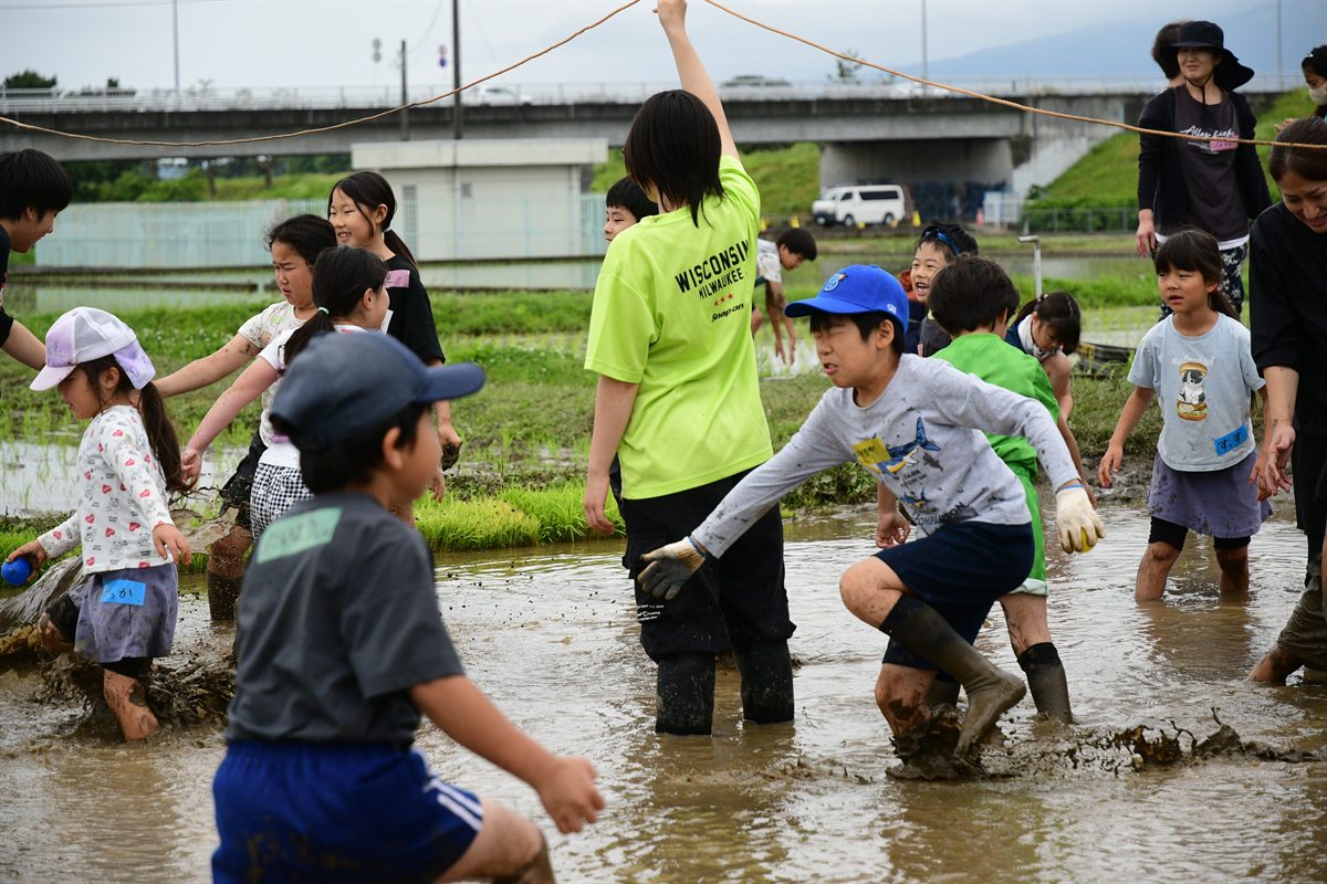 水を張った田んぼで、泥だらけになって走りまわる子どもたち