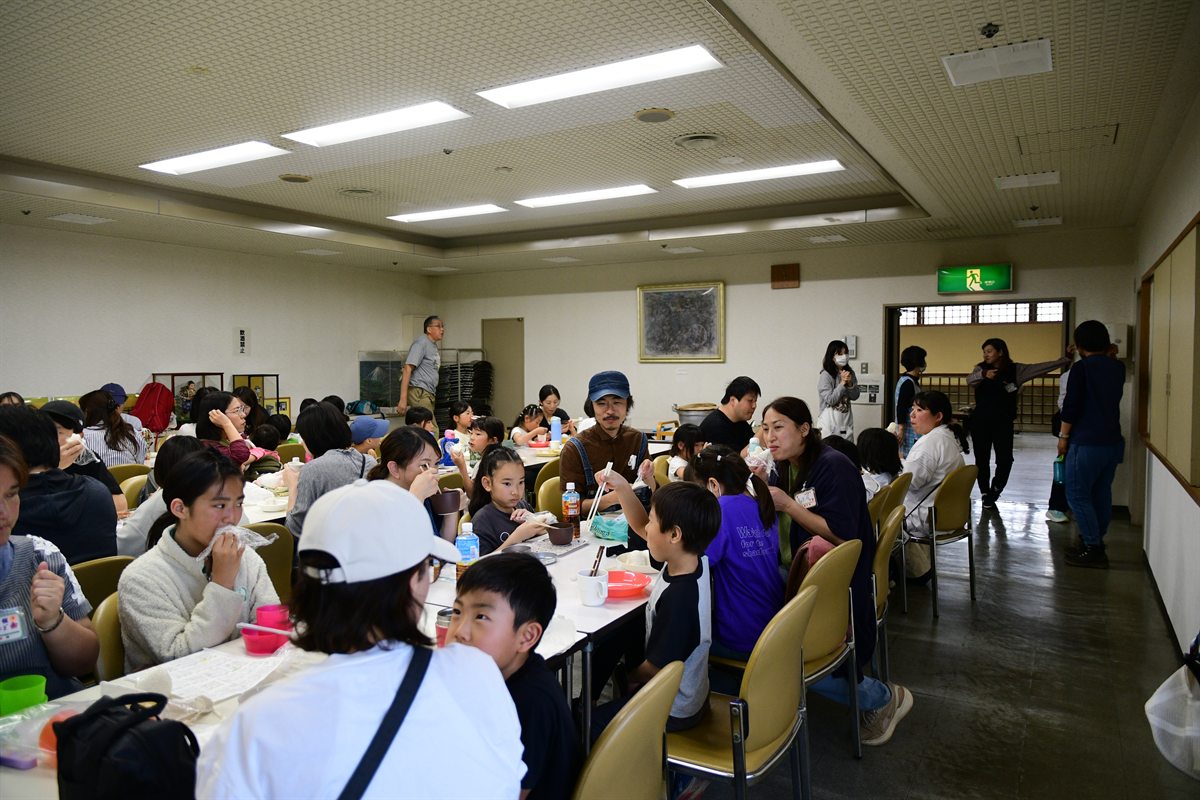 スクリーンに二宮金次郎の紙芝居を映して発表するスタッフと、見入る参加者たち